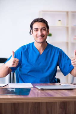 Klinikte çalışan genç erkek doktor.