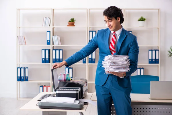 Jonge werknemer maakt kopieën bij kopieermachine — Stockfoto