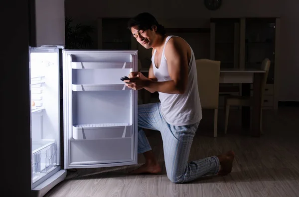 Человек нарушает диету ночью возле холодильника — стоковое фото