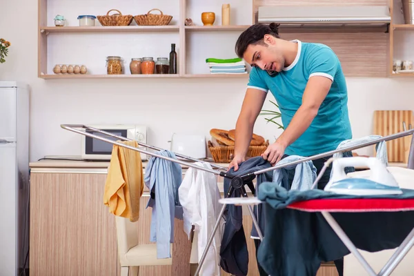 Ung man make gör kläder strykning hemma — Stockfoto