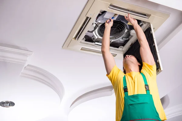 Joven reparador reparación de la unidad de aire acondicionado del techo —  Fotos de Stock