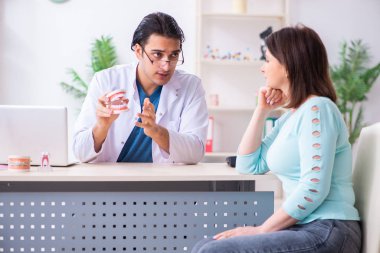 Orta yaşlı bir kadın, erkek doktor stomatoloğu ziyaret ediyor.