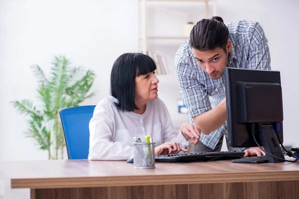 Junge männliche Mitarbeiter erklären alten Kolleginnen, wie sie zu uns kommen — Stockfoto