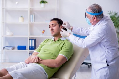 Erkek hasta doktor otolaryngologu ziyaret ediyor.