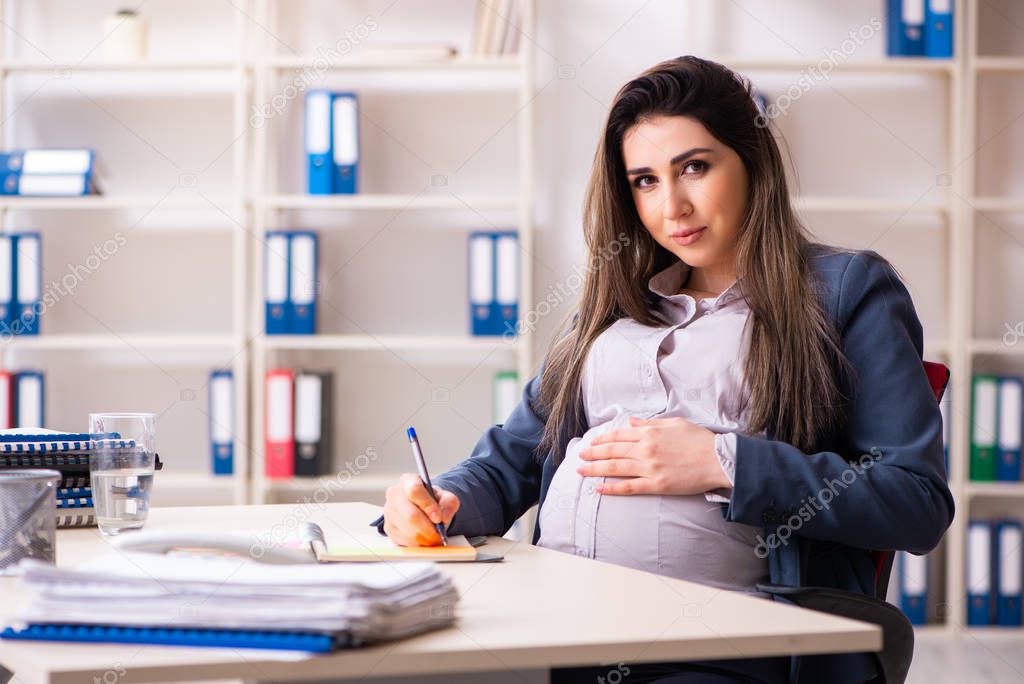 Young pregnant woman working in the office