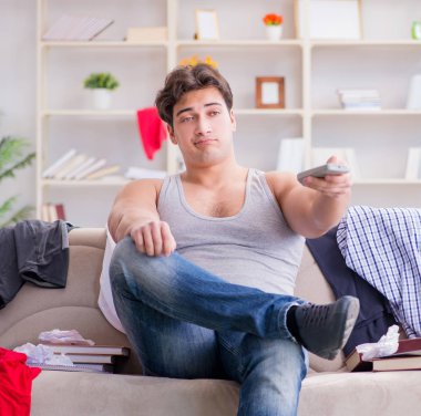 Genç adam dağınık bir odada çalışıyor.