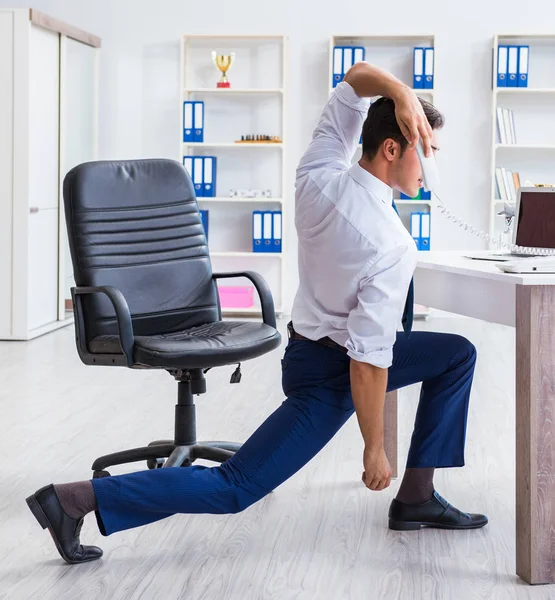 Giovane uomo d'affari che fa sport stretching sul posto di lavoro — Foto Stock