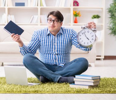 Genç yakışıklı adam evde yerde oturuyor.