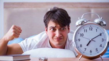 Yataktaki adam alarm yüzünden uykusuzluk çekiyor.