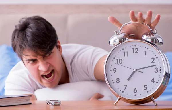 Man in bed gefrustreerd lijden aan slapeloosheid met een alarm cloc — Stockfoto