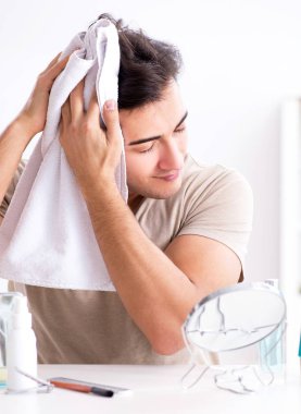 Genç yakışıklı adam aynaya bakıyor.