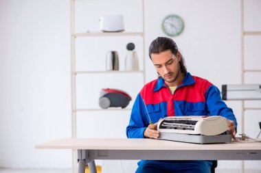 Genç erkek müteahhit atölyede klima tamiri yapıyor.