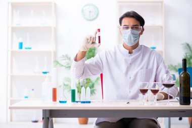 Male chemist examining wine samples at lab clipart