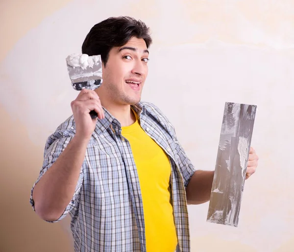 Hombre joven aplicando yeso en la pared en casa —  Fotos de Stock