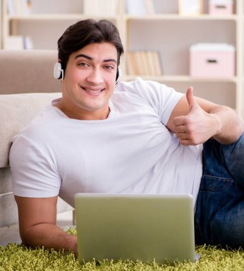 Evde, halı döşemesinde dizüstü bilgisayarda çalışan adam.