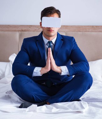 Yatak odasında sanal gerçeklik kulaklığı takan bir iş adamı.