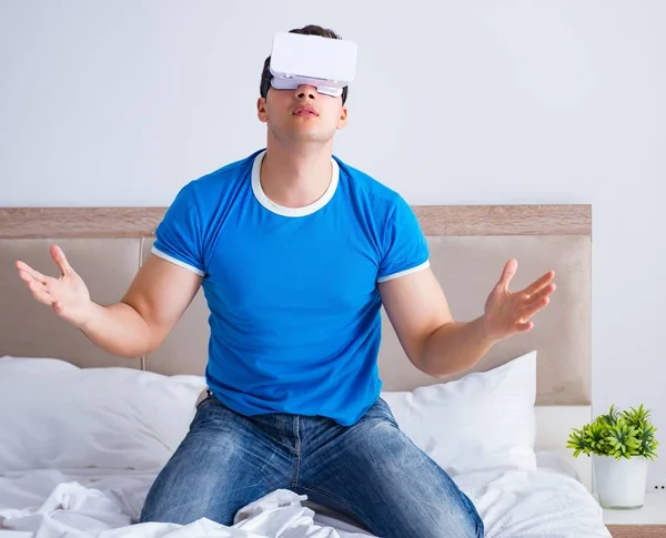 Jovem na cama vestindo um vr realidade virtual head set — Fotografia de Stock