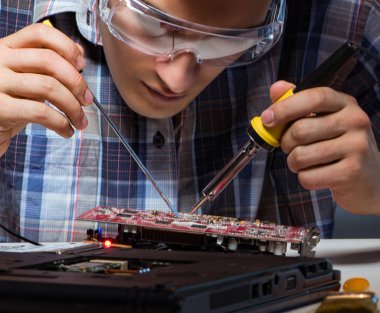 Genç tamirci ana yaban domuzunun elektrik parçalarını lehimliyor.
