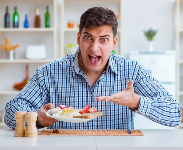 Joven marido comiendo comida insípida en casa para el almuerzo —  Fotos de Stock