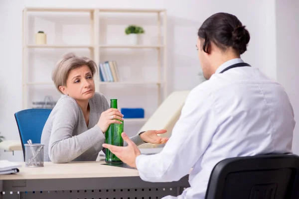 Жіночий алкоголік, що відвідує молодого лікаря-чоловіка — стокове фото