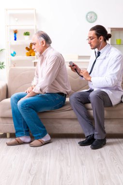 Genç erkek doktor eski hastayı ziyaret ediyor.