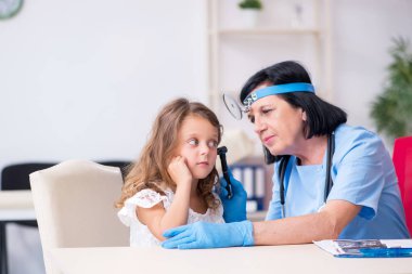 Küçük kız yaşlı kadın doktoru ziyaret ediyor.