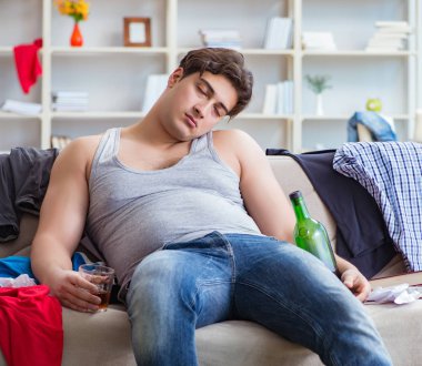 Dağınık bir odada alkol alan genç bir öğrenci.