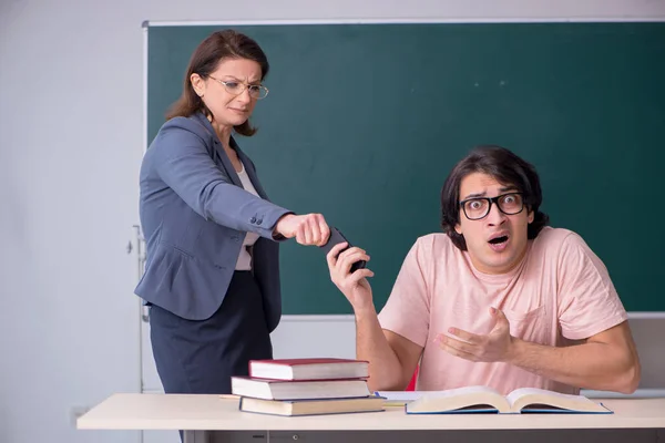 Gammal kvinnlig lärare och manlig student i klassrummet — Stockfoto