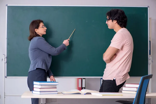 Old female teacher and male student in the classroom — Stock Photo, Image