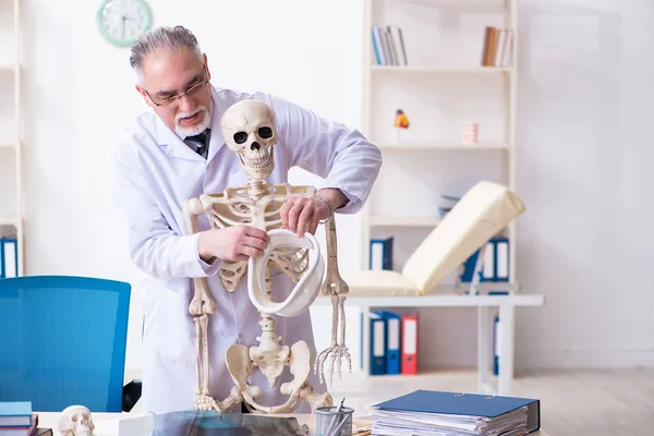 Médico varón envejecido con esqueleto — Foto de Stock