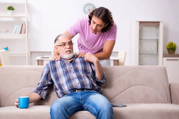 Jonge student en zijn oude opa thuis — Stockfoto