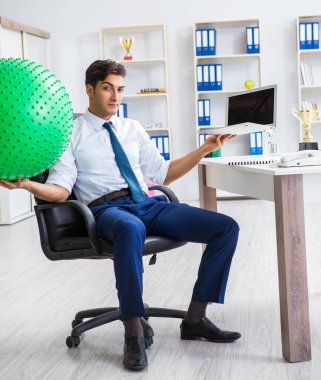 Genç işadamı iş yerinde spor yapıyor.