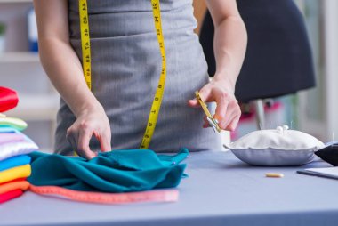 Kadın terzi dikiş dikmek için dikiş dikiyor.