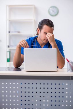 Klinikte çalışan genç erkek doktor.