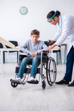 Genç erkek doktor pediatrist ve tekerlekli sandalyedeki çocuk.
