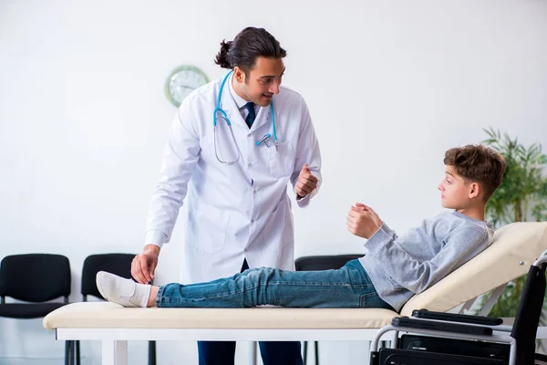 Genç erkek doktor pediatrist ve tekerlekli sandalyedeki çocuk. — Stok fotoğraf