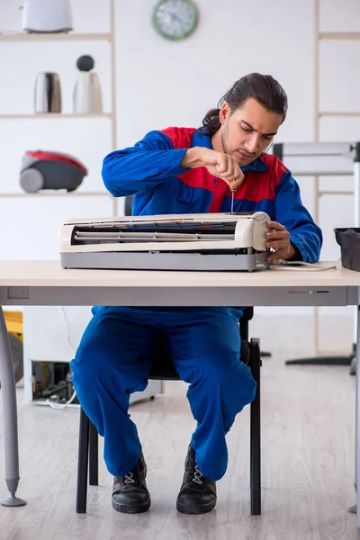 Jonge mannelijke aannemer repareert airconditioner in werkplaats — Stockfoto