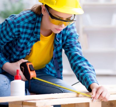 Tamirci kadın marangoz ahşap döşemeleri kesiyor.