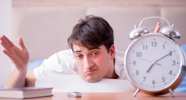 Yataktaki adam alarm yüzünden uykusuzluk çekiyor.