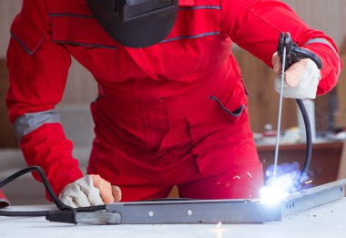 Kaynak tabancası elektrot ve kask takan genç bir tamirci.