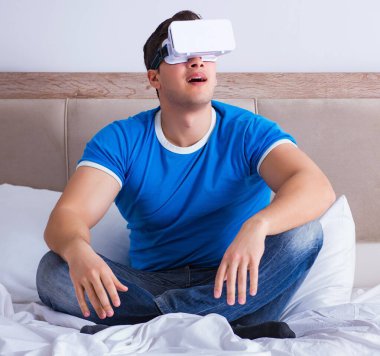 Yatakta sanal gerçeklik başlığı takan genç bir adam.