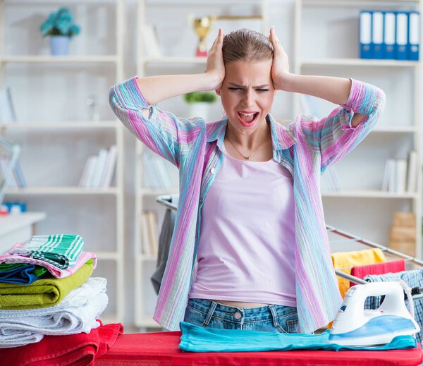 Sad woman ironing clothing at home