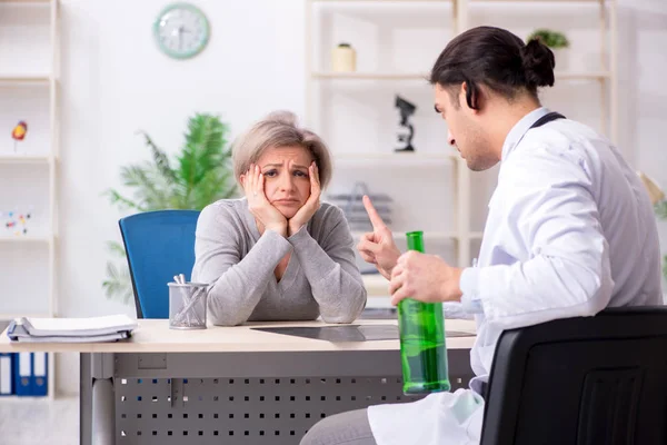 Female alcoholic visiting young male doctor — Stock Photo, Image