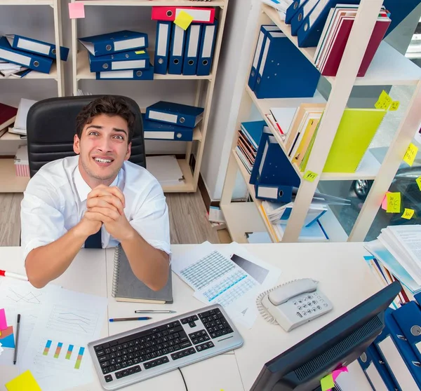 Empresário que trabalha no escritório com pilhas de livros e papéis — Fotografia de Stock
