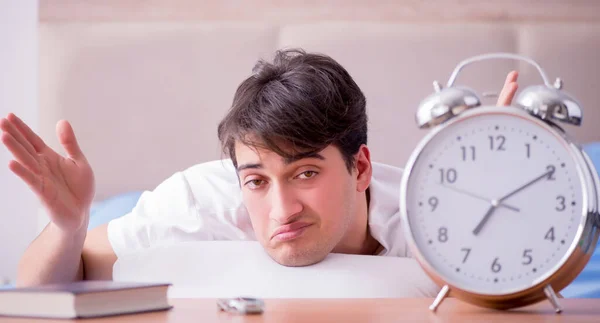 Hombre en la cama frustrado sufriendo de insomnio con un zueco de alarma — Foto de Stock