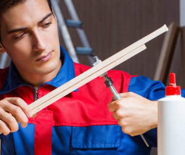 Genç adam ahşap parçaları DIY konseptinde yapıştırıyor.