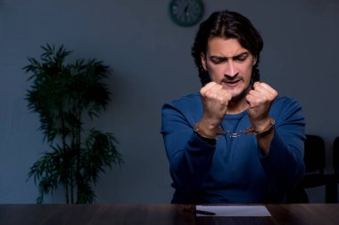 Genç mahkum karanlık odada oturuyor.