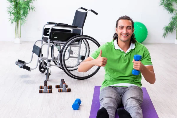 Young man in wheel-chair doing exercises indoors — Stock Photo, Image