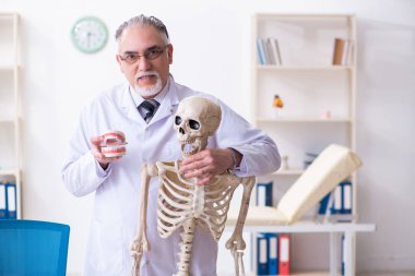 İskeleti olan yaşlı erkek doktor.