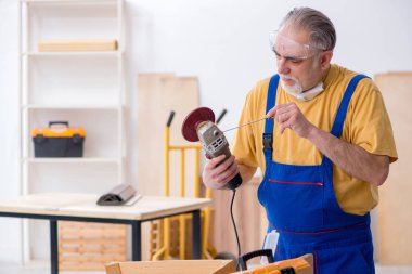 Yaşlı erkek marangoz atölyede çalışıyor.